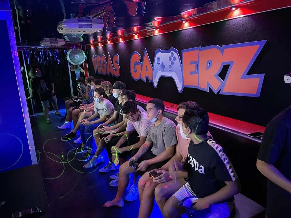 A packed bench of kids playing inside the trailer under blue and green laser lighting