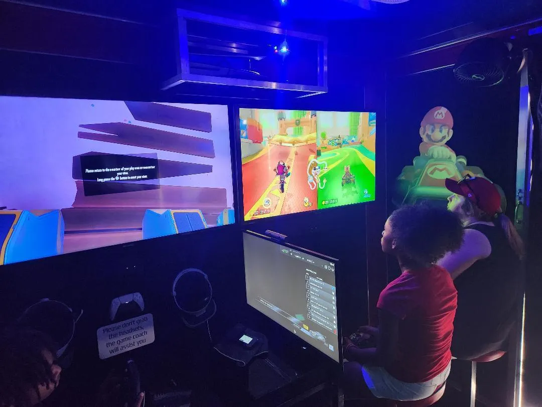 Kids playing Mario Kart at the trailer’s screens under blue neon